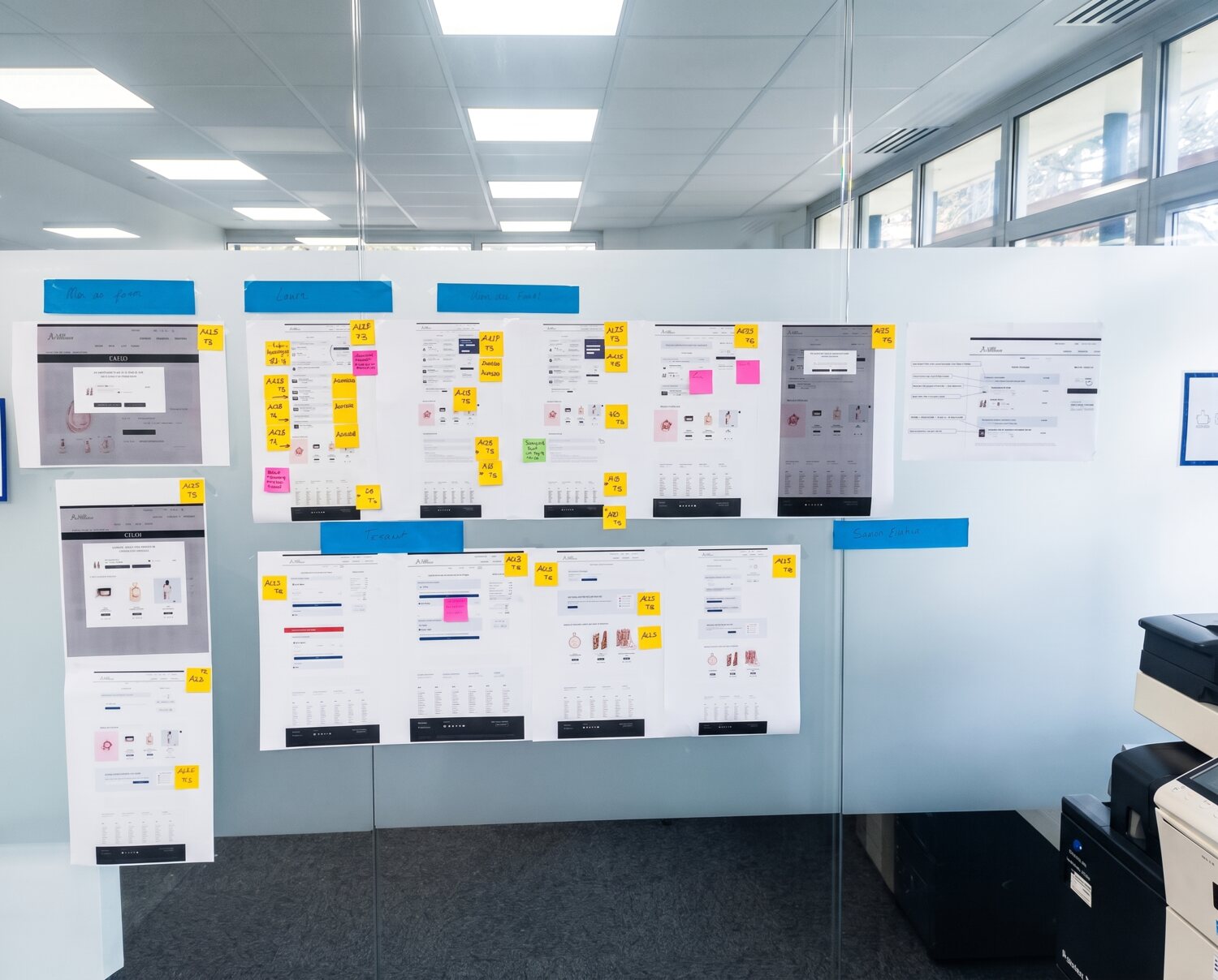 Mur de wireframes des écrans Paris Aéroport, annotés en post-its lors d'une revue UX