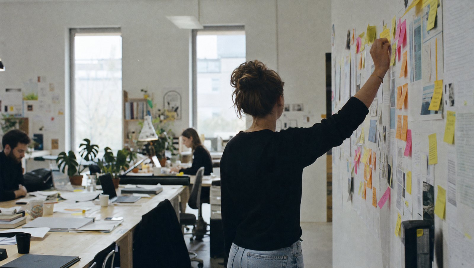 Mur de post-its colorés pendant un atelier, une main place une note